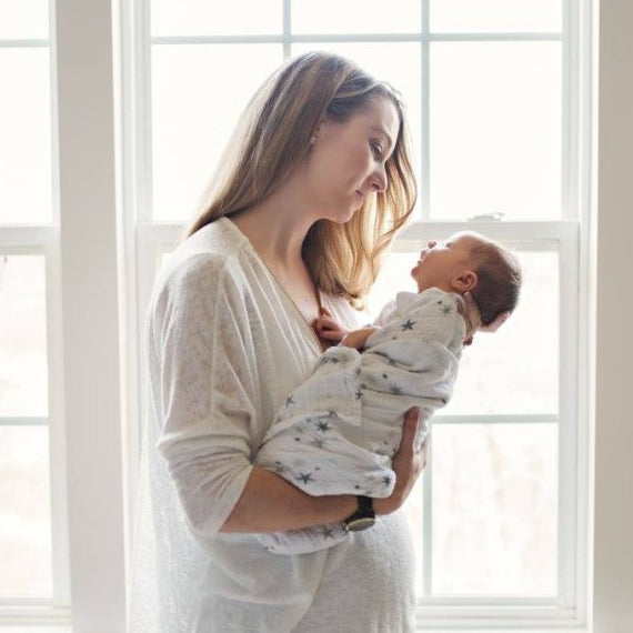 A new mom holding her newborn baby looking at him.