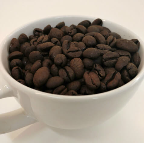 White mug with Talking Crow Coffee Roasters roasted decaf beans inside