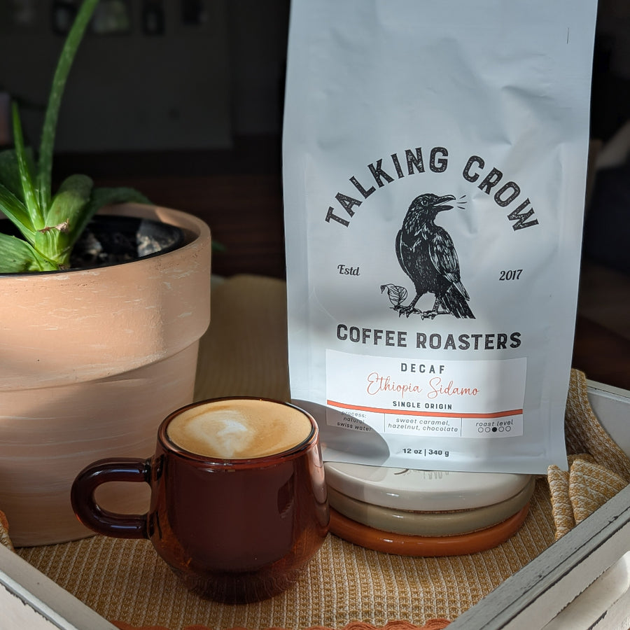 Coffee bag labeled 'Talking Crow Coffee Roasters' next to a cup of coffee on a table.