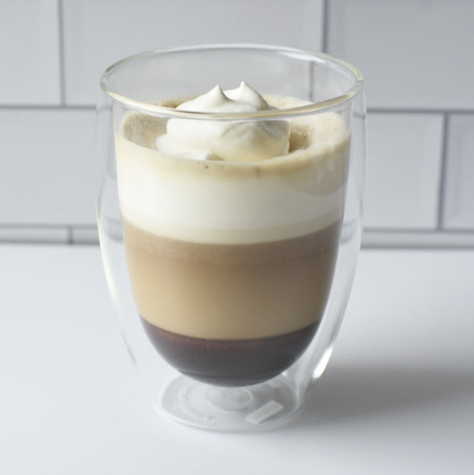 Tres Leches Coffee Drink in glass with layers of black coffee, sweetened condensed milk, evaporated milk, and whipped cream.