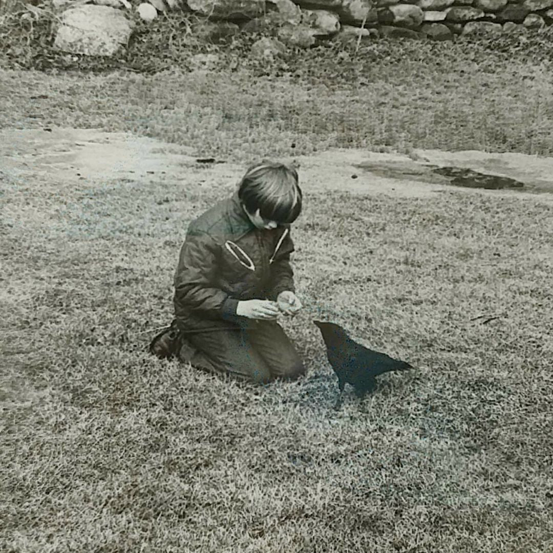 Vintage picture of young Eric on the grass with his pet, Tony the Talking Crow