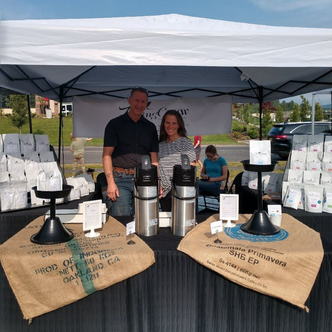 Eric and Carol standing behind their Talking Crow Coffee Roasters products at the Monroe Farmers' Market