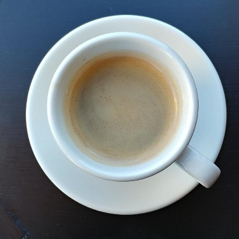 white cup and saucer with espresso on a black background