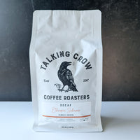 White coffee bag with 'Talking Crow Coffee Roasters' branding on a dark background